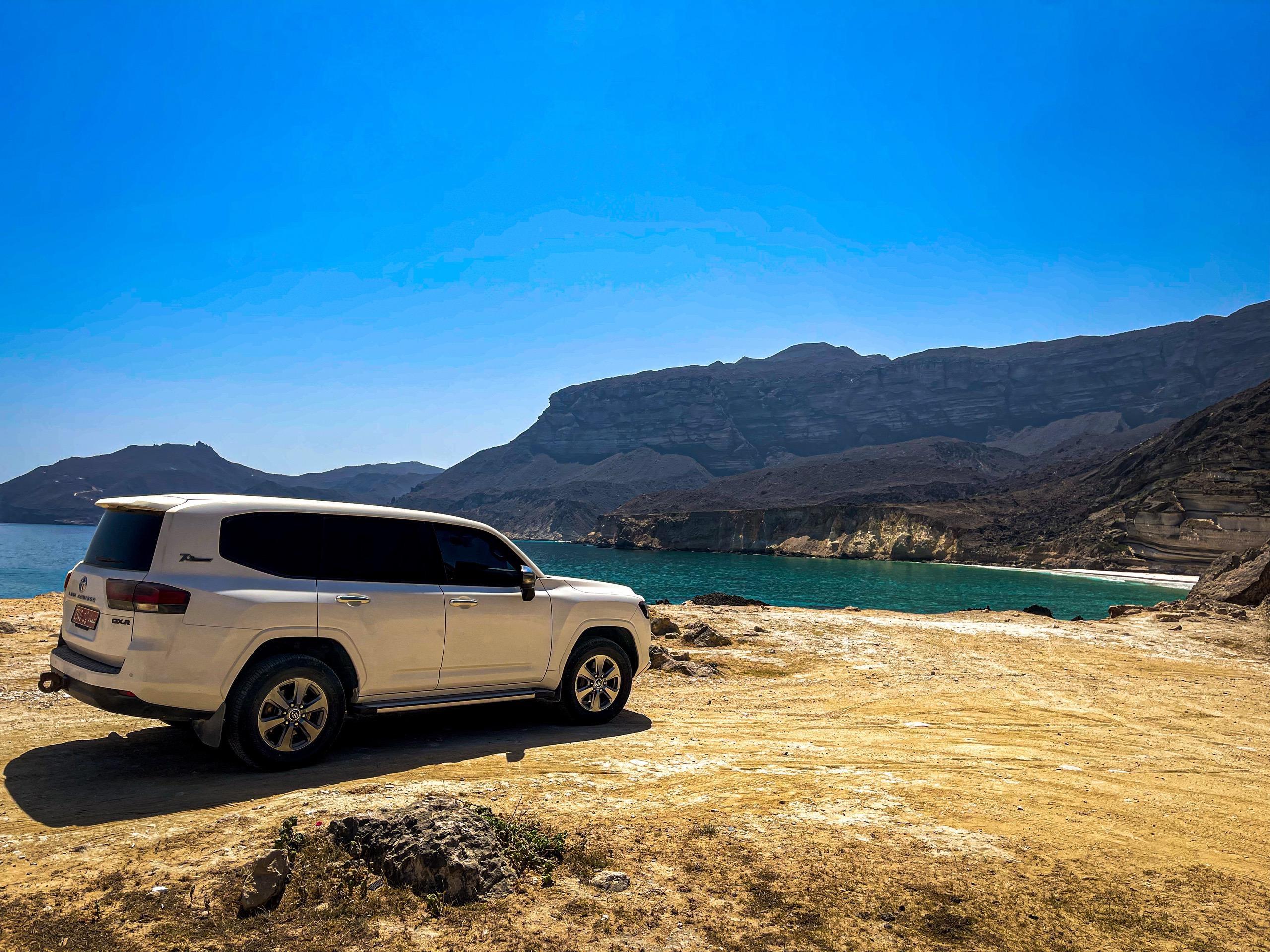 Mit dem 4x4 auf einer Klippe über einer türkisblauen Bucht, Oman