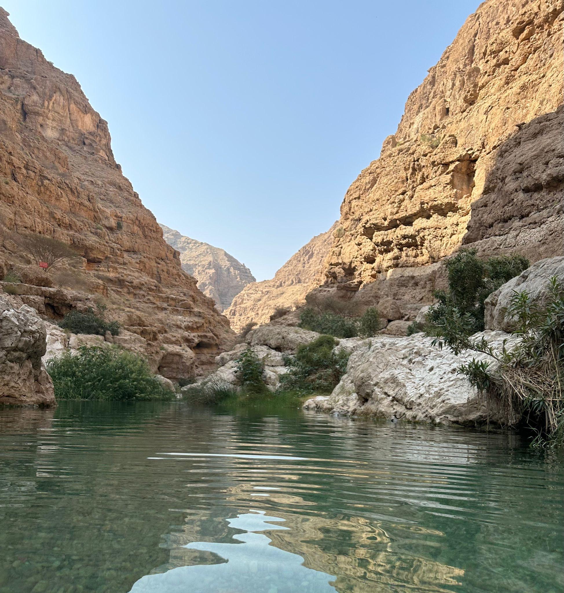 Türkisfarbenes Wasser zwischen den steilen Felswänden eines Wadis